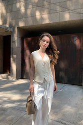 a lady in a beige vest and a pair of white pants